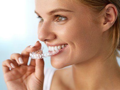 Woman placing a clear aligner over her teeth