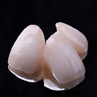 Three ceramic dental crowns against black background
