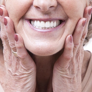 Close up of smiling senior woman touching her face