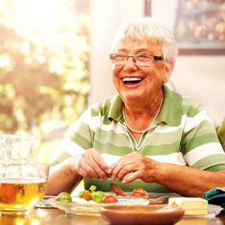 Senior woman smiling at dining table with dentures in Pembroke Pines