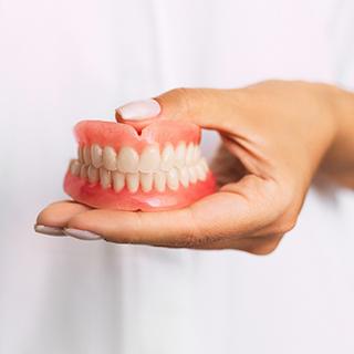 Woman holding full dentures