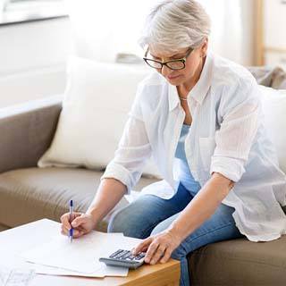 Woman typing on calculator while filling out paperwork