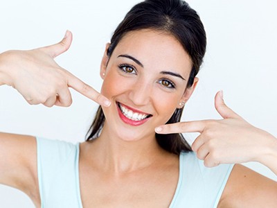 young woman pointing to her smile with tooth-colored fillings in Pembroke Pines