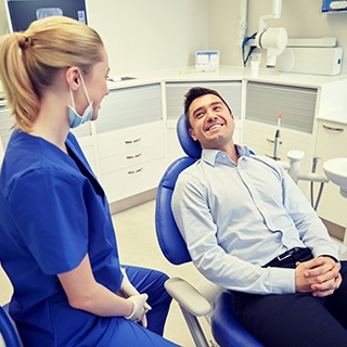 man in light blue dress shirt smiling at dentist