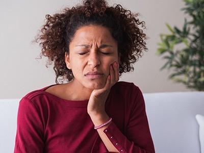 person holding their mouth due to pain caused by gum disease