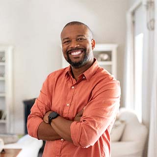 Man standing in front of a couch smiling with dental implants in Pembroke Pines