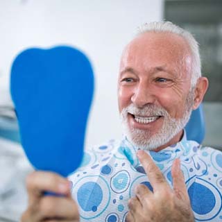 senior man admiring his new smile with dental implants in Pembroke Pines