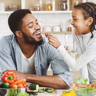 child feeding their dad a cherry tomato