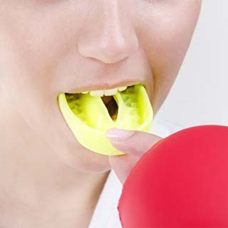 person putting a yellow mouthguard over their teeth