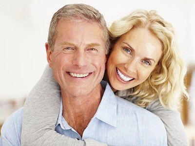 An older couple smiling and hugging with implant dentures in Pembroke Pines