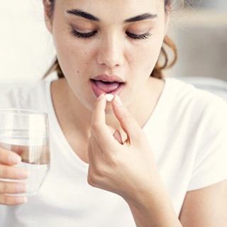 woman taking pain medication with water