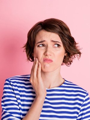 Woman rubbing jaw looking uncomfortable