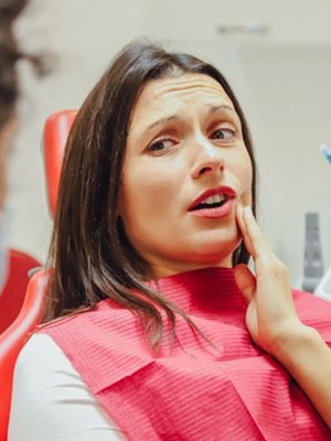 Patient rubbing jaw and explaining symptoms to dentist
