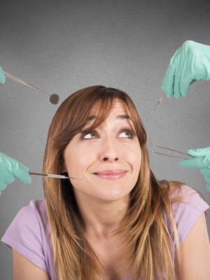 Woman looking nervous as multiple dentists approach with dental tools