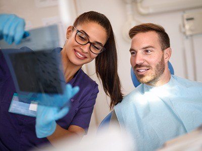 Dental team member and patient looking at x rays during preventive dentistry checkup