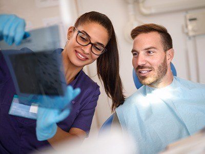 Dental team member and man looking at x-rays