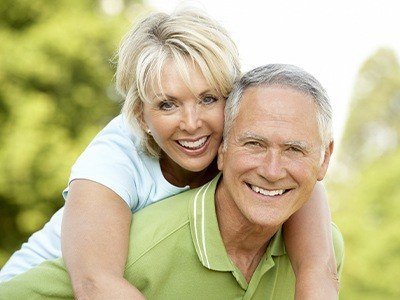 Smiling older man and woman outdoors after restorative dentistry