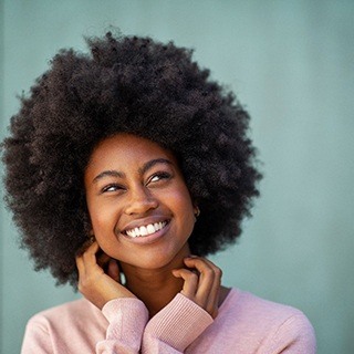 person smiling and holding their hands up to their chin