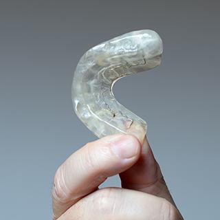 Hand holding clear occlusal splint