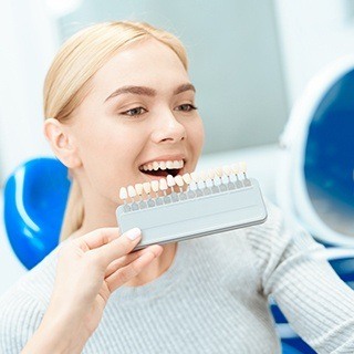 Woman smiling next to tooth shade chart