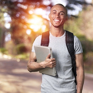 students smiling and holding a laptop