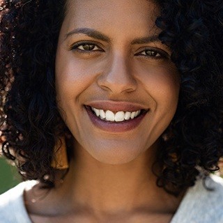 person with curly dark hair smiling