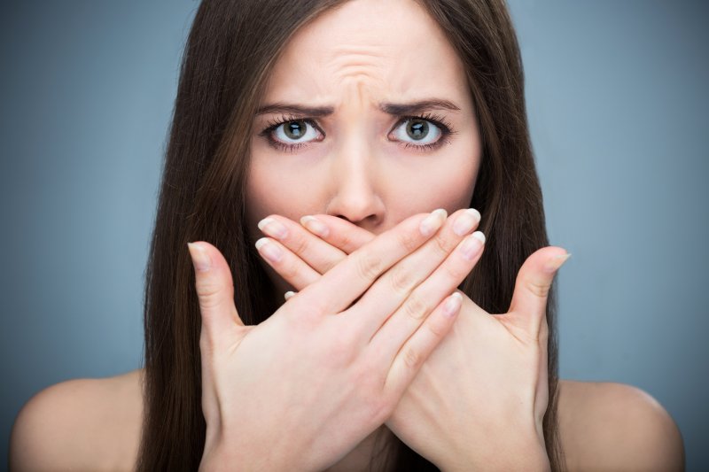 young woman covering her mouth in shame